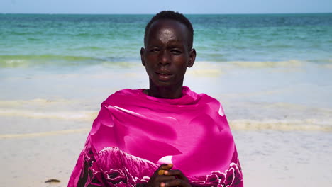 indigenous african man in pink clothing on white sand beach, close up