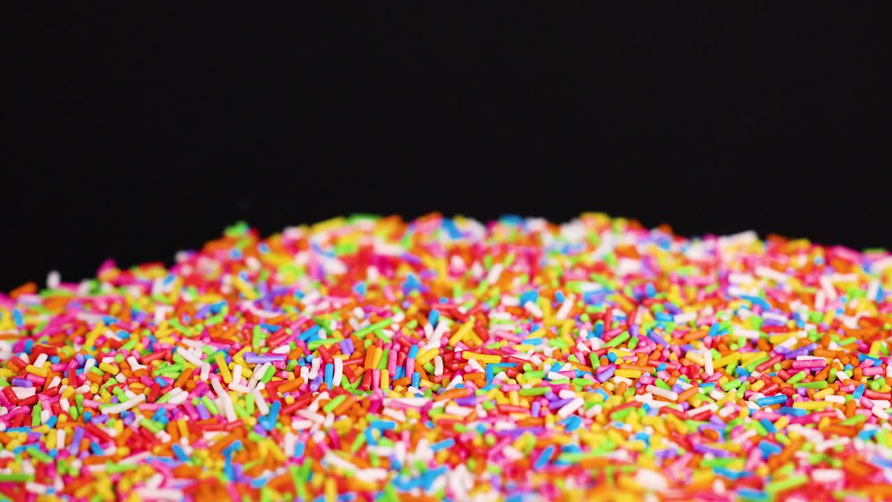 Zuccherini colorati che cadono a cascata su uno sfondo scuro