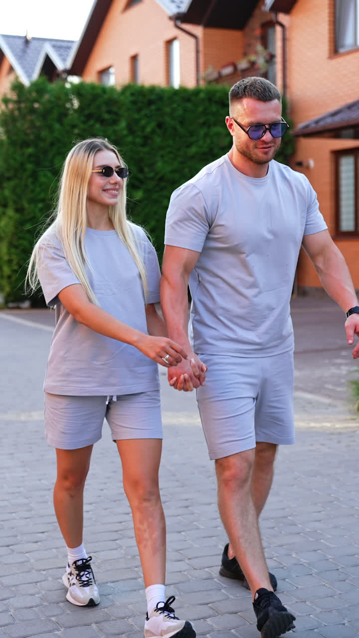 Young couple on a sunny walk. A young couple strolls hand in hand along ...