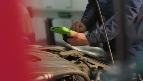 car service electrician or mechanic uses a tablet computer with futuristic interactive diagnostics software. inspecting the vehicle in order to find broken components in the engine bay of modern car