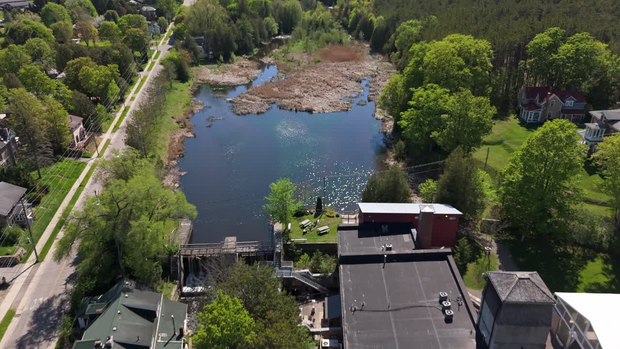 Drone flyover of Alton Mill buildings with green surroundings, roads, and tree-lined paths
