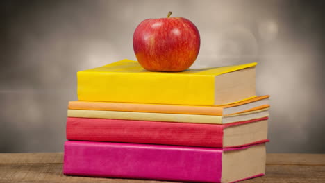 animación de una pila de libros con una manzana roja en la parte superior sobre luces brillantes