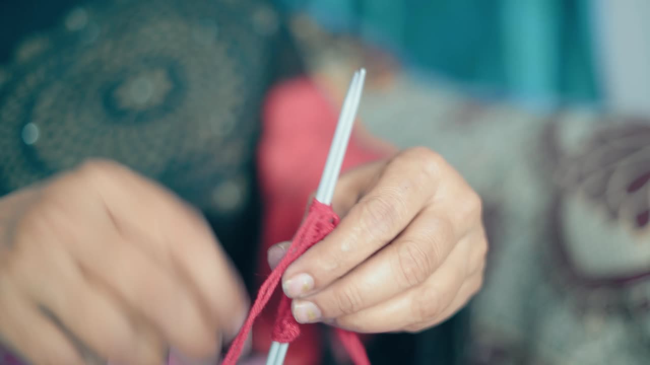 빨간 모직과 바늘 공예품으로 첫 번째 줄로 뜨개질을 시작하는 여자