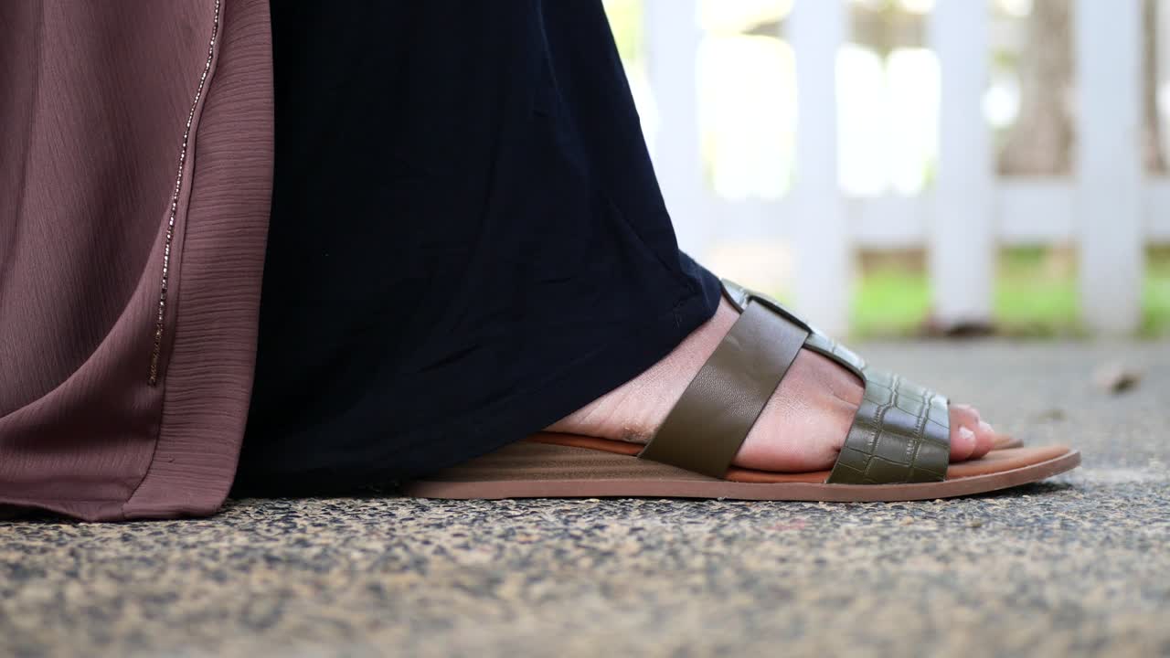 Sidebillede af pigefødder med sandaler udendørs.