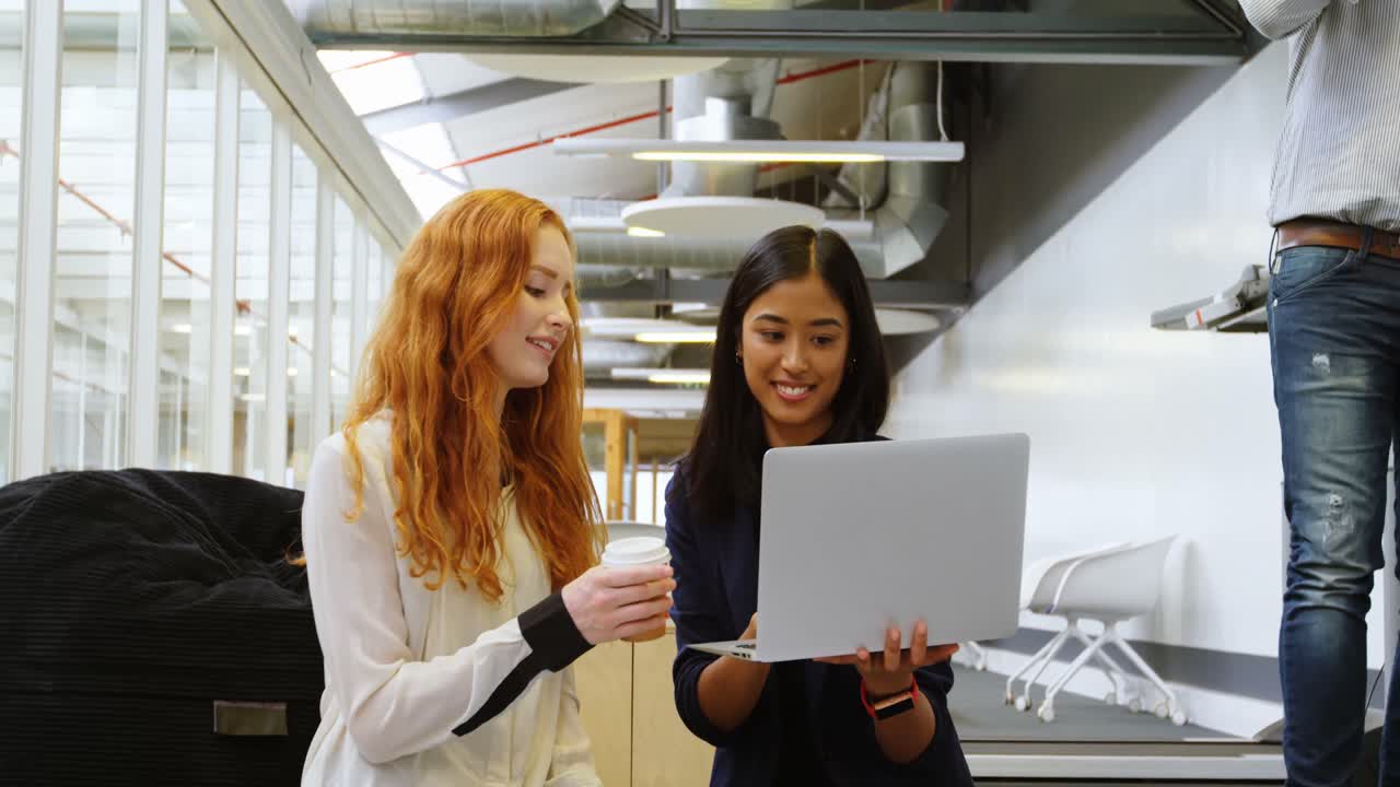 Female executives discussing over laptop 4k