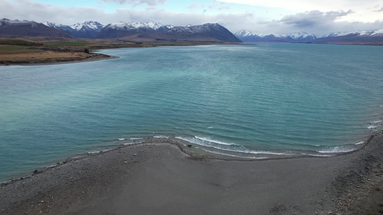 Lake Tekapo In South Island Of New Zealand - Turquoise Lake With Waves Splashing On Sandy Shore. drone shot