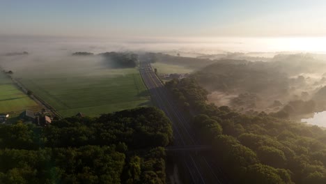 aerial view of a foggy morning landscape with a highway, forests, and fields