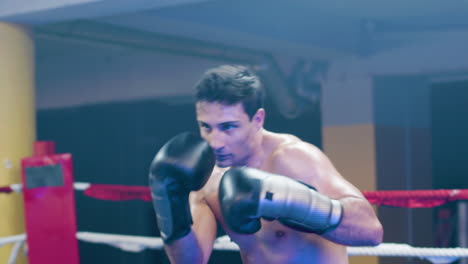 joven atractivo haciendo lucha de sombras en el ring de boxeo
