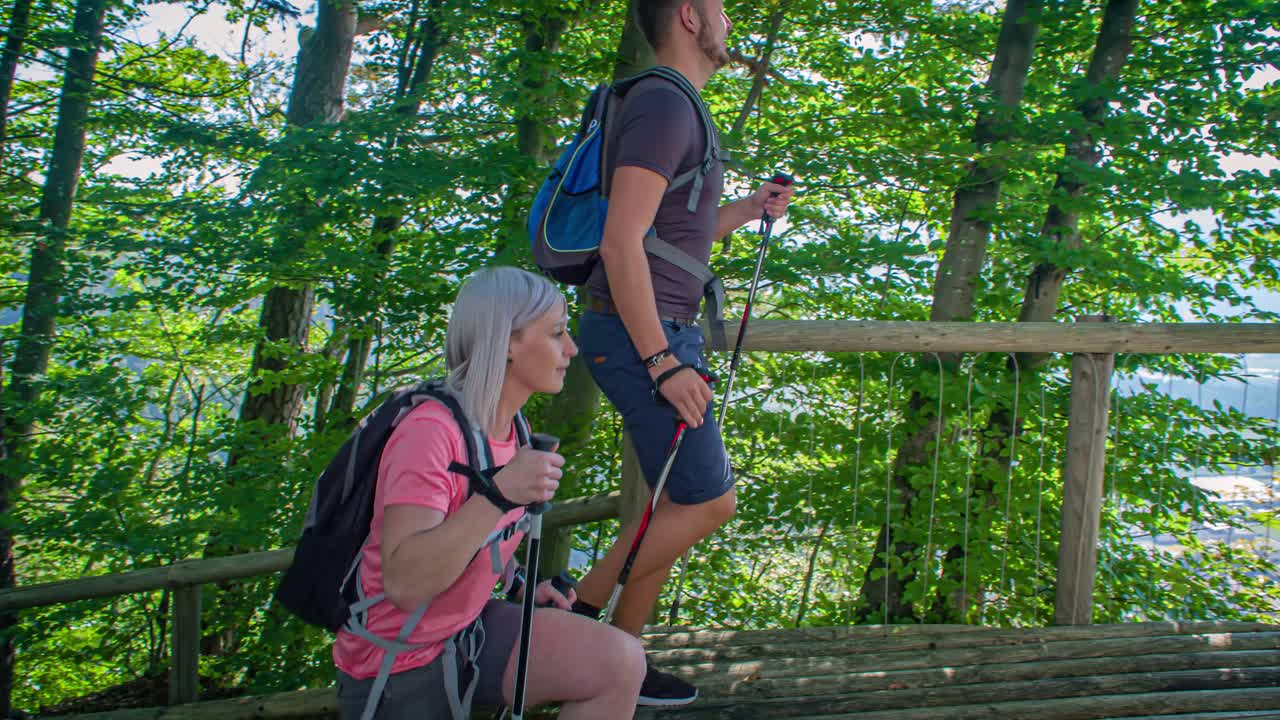 happy couple hiking in the forest, amazing view of Radlje ob Dravi and mountains hiking poles