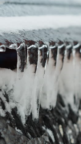 close-up of frosted car window covered in icicles and snow with blurred winter background, capturing frozen textures, icy details, and the cold atmosphere of an overcast day