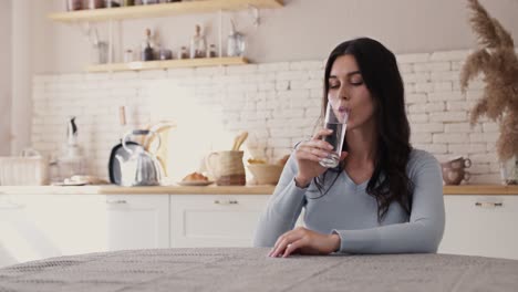 woman drinking water in kitchen