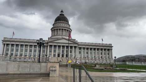 outside looking at front of utah state capital building on an overcast gloomy day seeing a few protesters standing around as camera starts panning and moving off to the right