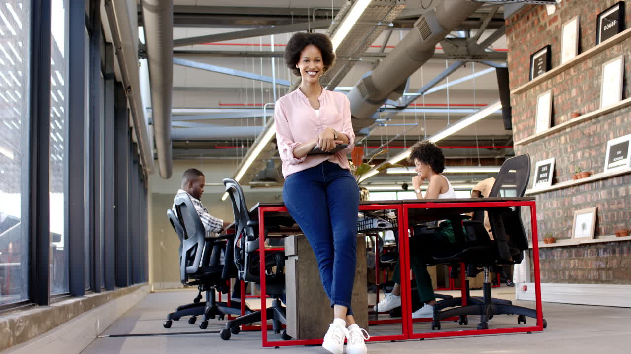 African American woman standing confidently in modern office, smiling at camera