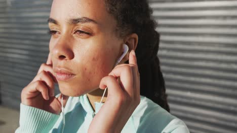 mujer afroamericana en ropa deportiva con auriculares en un día soleado