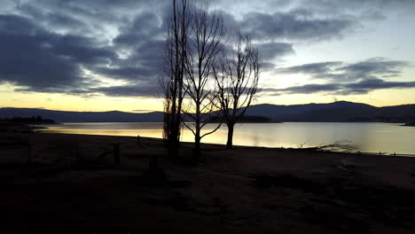 Puesta-De-Sol-Sobre-El-Lago-Y-Las-Montañas-De-Jindabyne,-Australia--antena