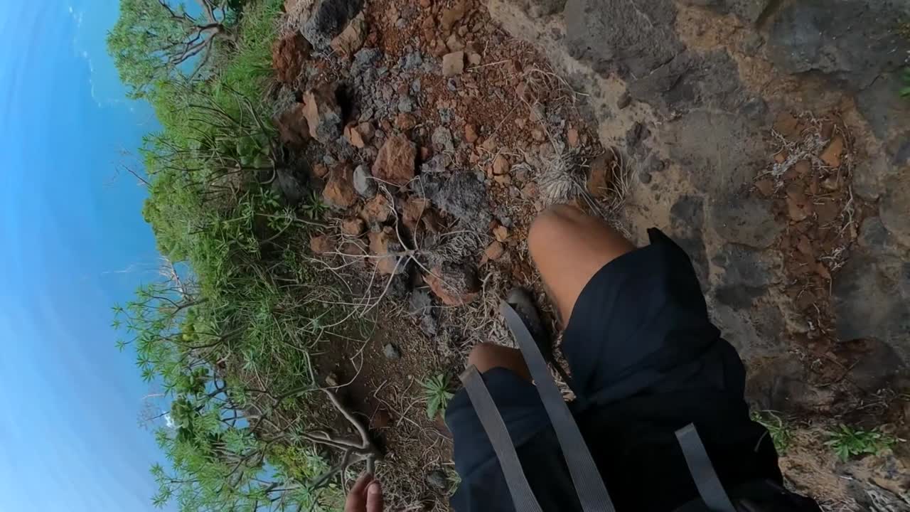 pov de las piernas y los zapatos de un hombre atlético, caminando por el sendero de tierra al borde de una montaña en madeira