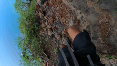 pov de las piernas y los zapatos de un hombre atlético, caminando por el sendero de tierra al borde de una montaña en madeira
