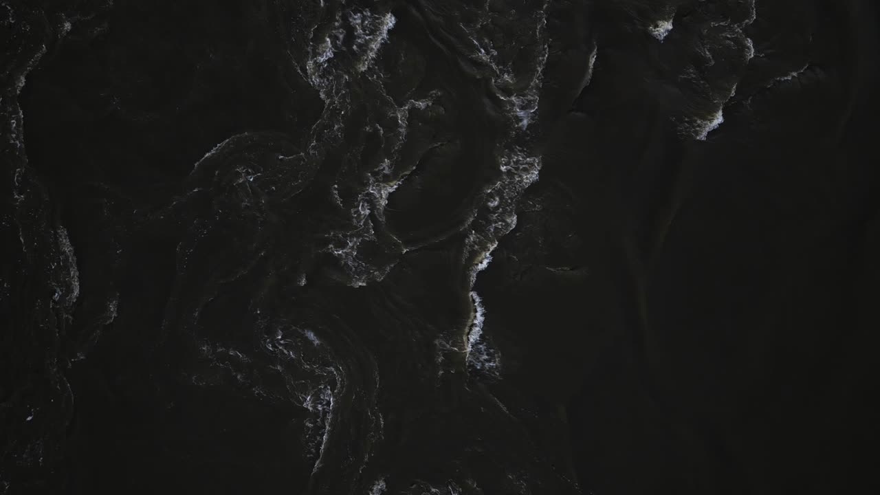The turbulent swirling waters of the Mississippi River as seen from above. The dark muddy water is rushing by, creating an interesting visual where the undertow and swirls can be seen