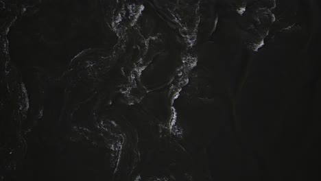 the turbulent swirling waters of the mississippi river as seen from above. the dark muddy water is rushing by, creating an interesting visual where the undertow and swirls can be seen