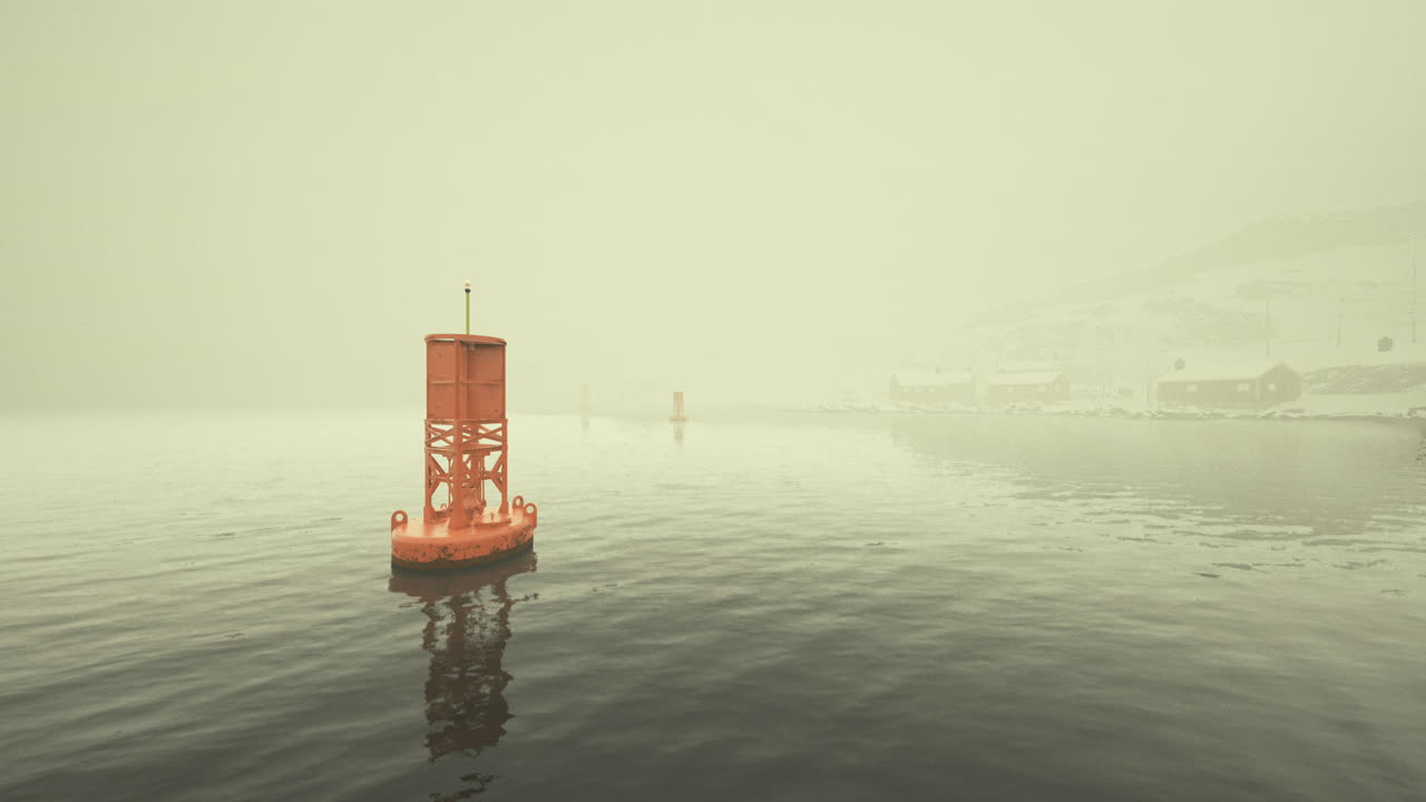 Foggy morning with an orange buoy navigating calm waters in a harbor