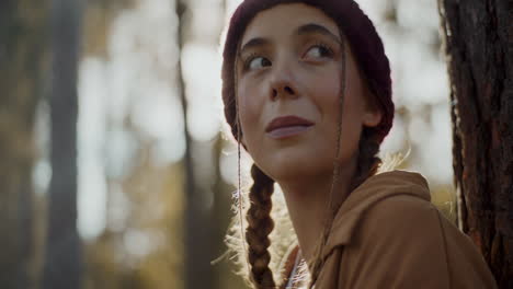 mujer con cabello trenzado mirando alrededor en el bosque