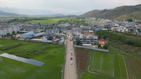 drone footage panning over a small village next to the crop fields cultivated by the traditional bai tribe