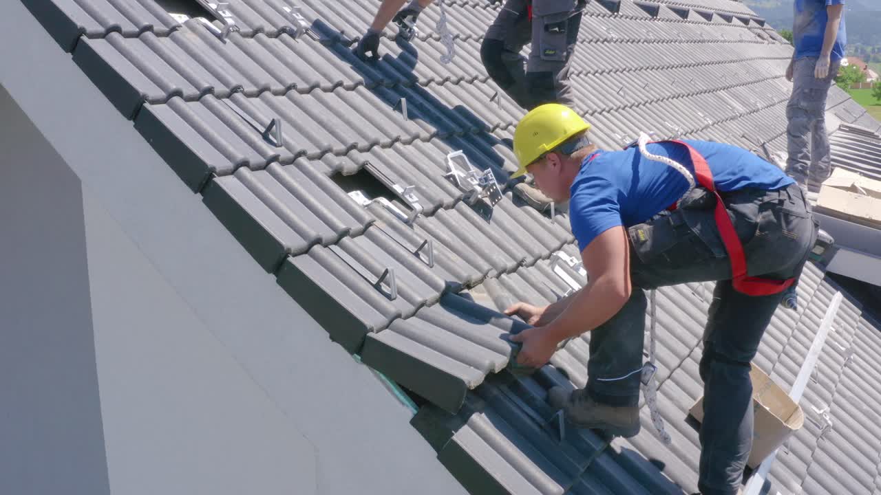 Worker on edge of roof removes tile, preparing for solar panel installation