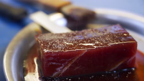 seasoning marinated pieces of tuna for asian noodles in a restaurant by a chef