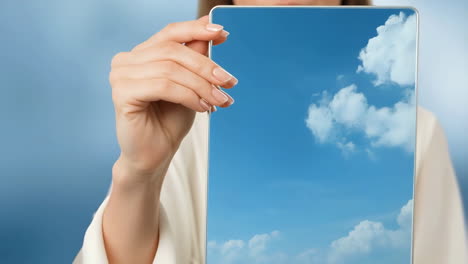 person holding a tablet displaying a blue sky with clouds