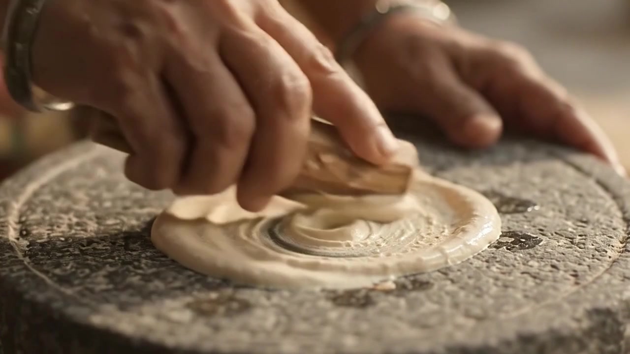 Person Grinding Sandalwood Paste on Traditional Stone Slab