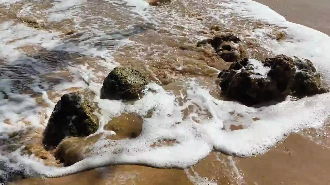 Onde dell'oceano che si infrangono contro le rocce su una spiaggia sabbiosa