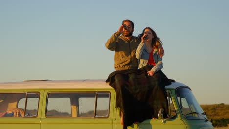 young couple drinking beer during sunset on beach 4k