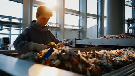 работник перерабатывающего завода, сортирующий пластиковые отходы