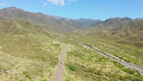 solo coche que viaja a través de un camino solitario en un paisaje montañoso del desierto