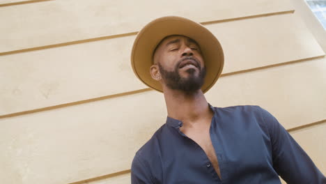 afro caribbean man with panama hat standing in the old town street and looking around