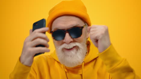 Mature-man-dancing-inside.-Joyful-old-guy-with-phone-having-fun-indoors.