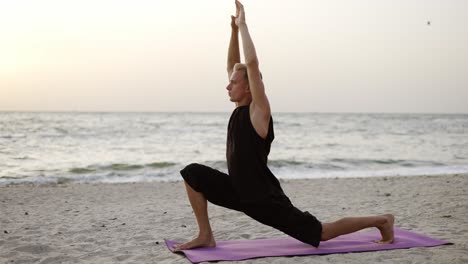 a young man practices yoga while standing on a sports mat at dawn. performing a specific exercise. body stretch. free time, rest