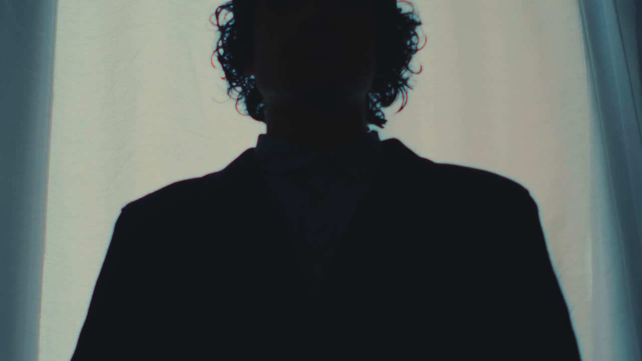 Anonymous silhouette against bright window with minimal cinematic mood