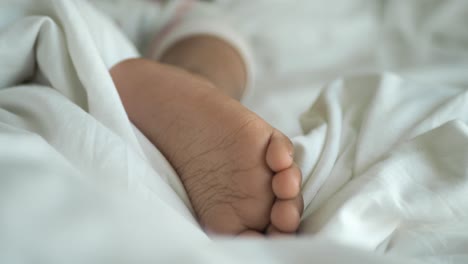 close up of a baby's foot sleeping in a white bed