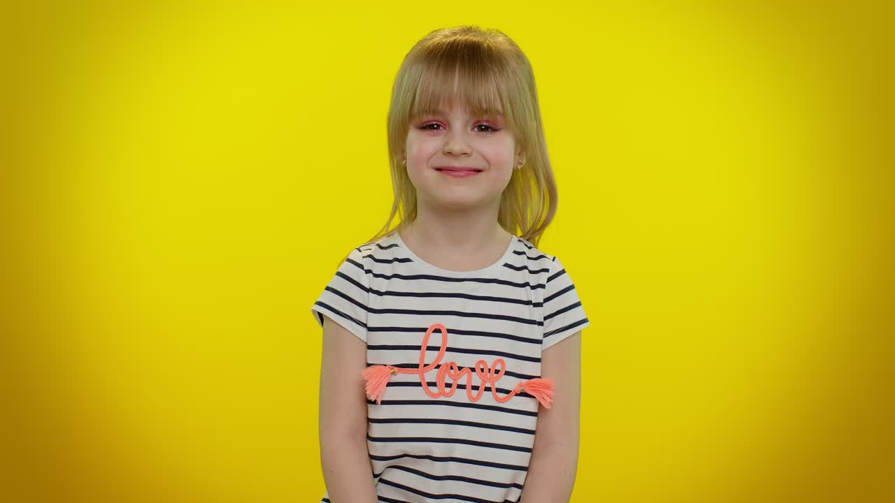 una niña linda sonriendo con una camisa de amor en un fondo amarillo