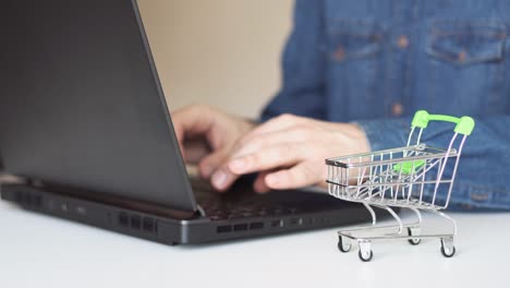 close up of man hands using laptop making online payment with shopping cart on table. online shopping concepts.