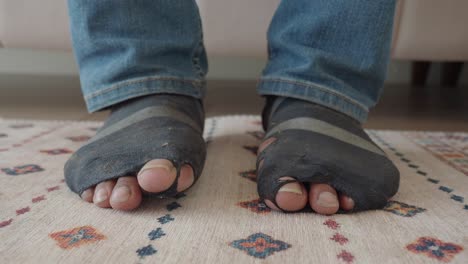 person's feet in worn out, ripped socks