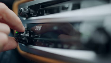 persona de primer plano ajustando la temperatura en el coche. mano usando la perilla del aire acondicionado