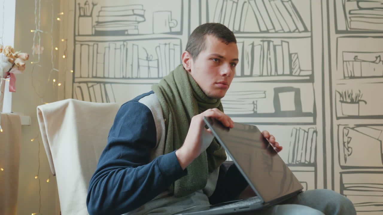 Uomo caucasico che ispeziona lo schermo di un laptop, mentre uno studente avvolto in una sciarpa sbircia da dietro il coperchio, in un accogliente soggiorno con carta da parati a libreria e lucine fatate. Curiosa risoluzione dei problemi, leggera tensione, atmosfera domestica tranquilla.
