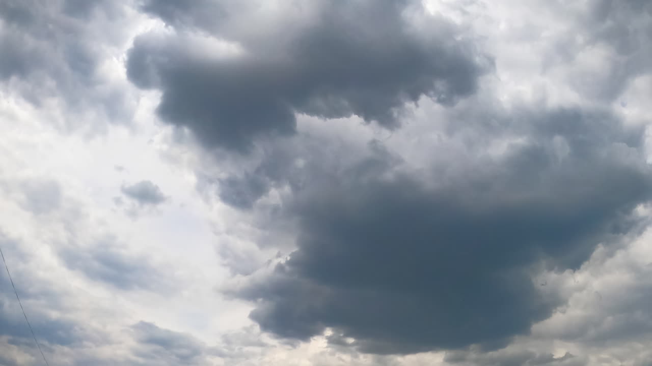 Stormy grey clouds accumulating in the atmosphere. Cumulus cloudscape formation in the sky from low angle view. Timelapse.