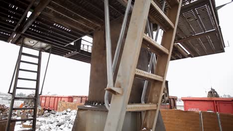 Under-a-snowy-sky,-a-robust-industrial-setting-with-metal-structures-and-a-large-gripping-crane