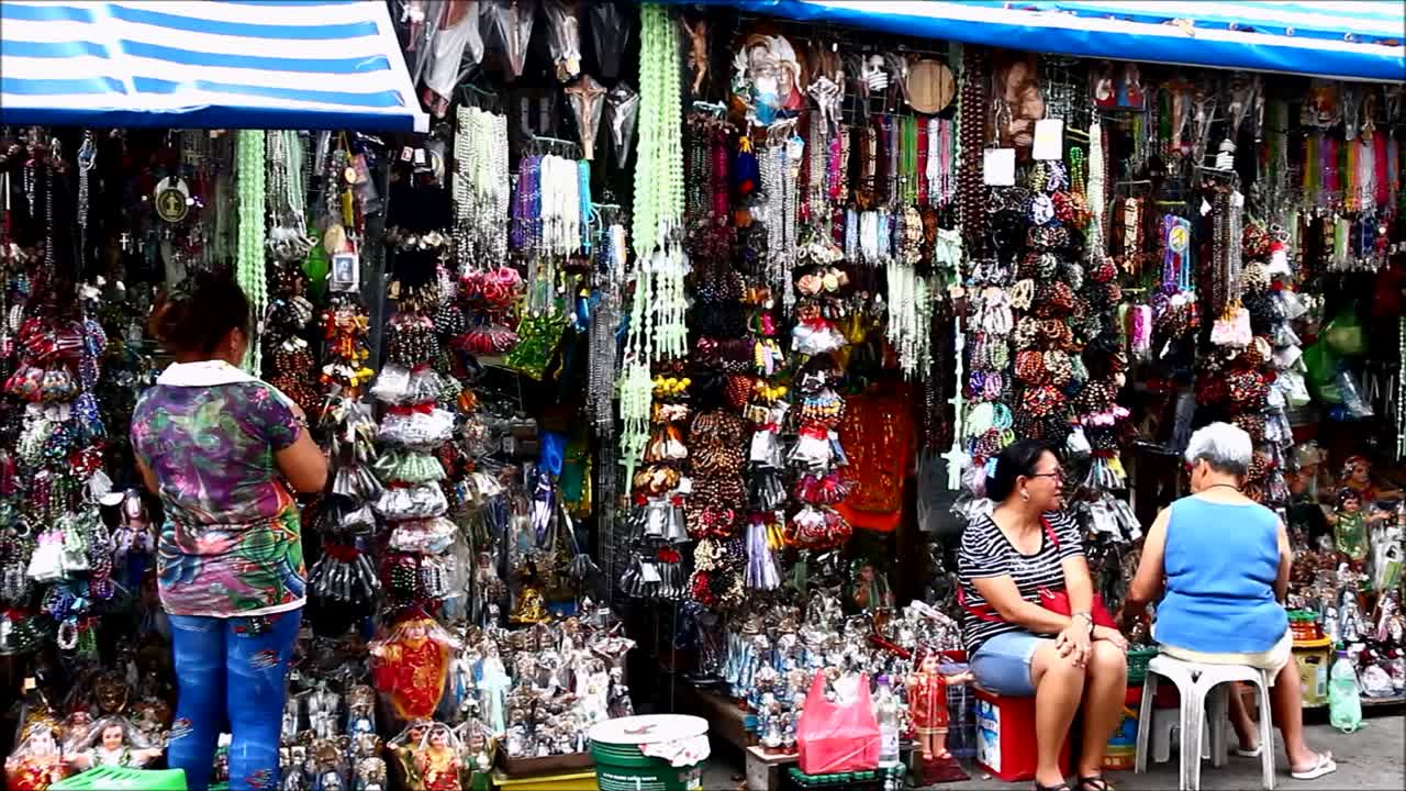 People shopping at a street market stall selling religious items and souvenirs
