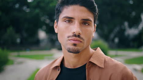 serious guy posing park portrait. young man face looking camera standing nature