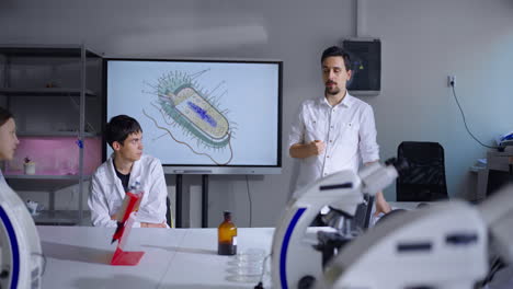 a biology teacher explains a bacteria cell diagram to students in a classroom