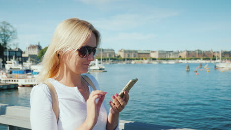 The-Woman-Blogger-Communicates-Via-Video-Chat-Walks-The-Bridge-Across-The-Río-Against-The-Backdrop